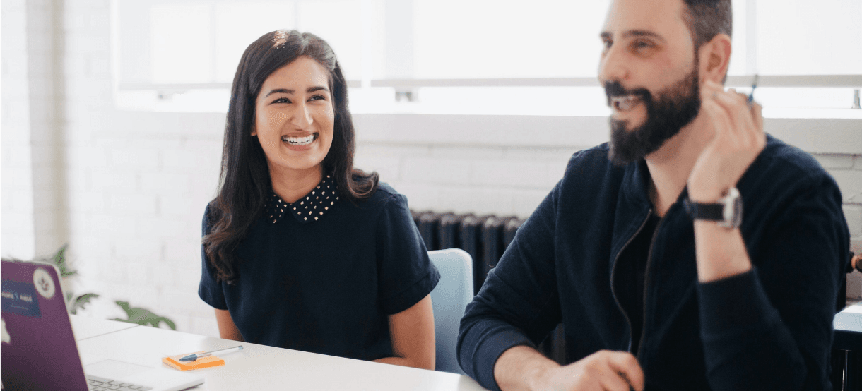 people holding pens, in front of their laptops, in the office and honestly laughing